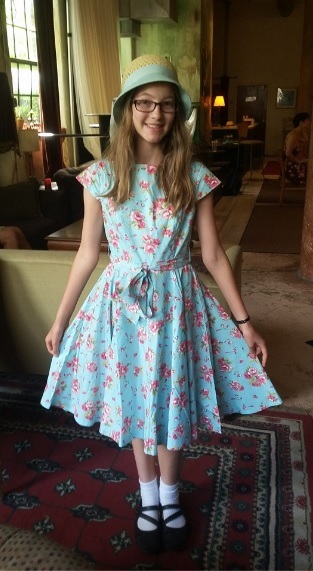 Kiera Burke dressed as Honoria Wales in a vintage light blue dress with pink flowers